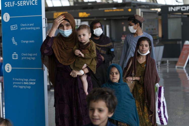 Families evacuated from Kabul, Afghanistan, walk through the terminal before boarding a bus after they arrived at Washington Dulles International Airport, in Chantilly, Va., on Friday. 