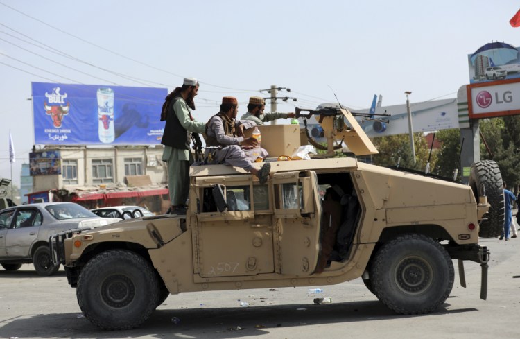 Taliban fighters stand guard in front of the Hamid Karzai International Airport, in Kabul, Afghanistan, on Monday. The Taliban captured an array of modern military equipment when they overran Afghan forces who failed to defend district centers. 