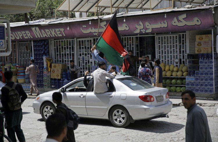 Afghans wave a black, red and green banner in honor of the Afghan flag – a banner that is becoming a symbol of defiance since the Taliban have their own flag, on Afghan Independence Day, in Kabul, Afghanistan, on Thursday.