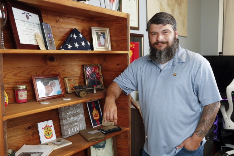 Lance Cpl. William Bee poses Wednesday for a photo next to a bookshelf that displays items from his families military service including his Purple Heart at his home in Jacksonville, N.C.