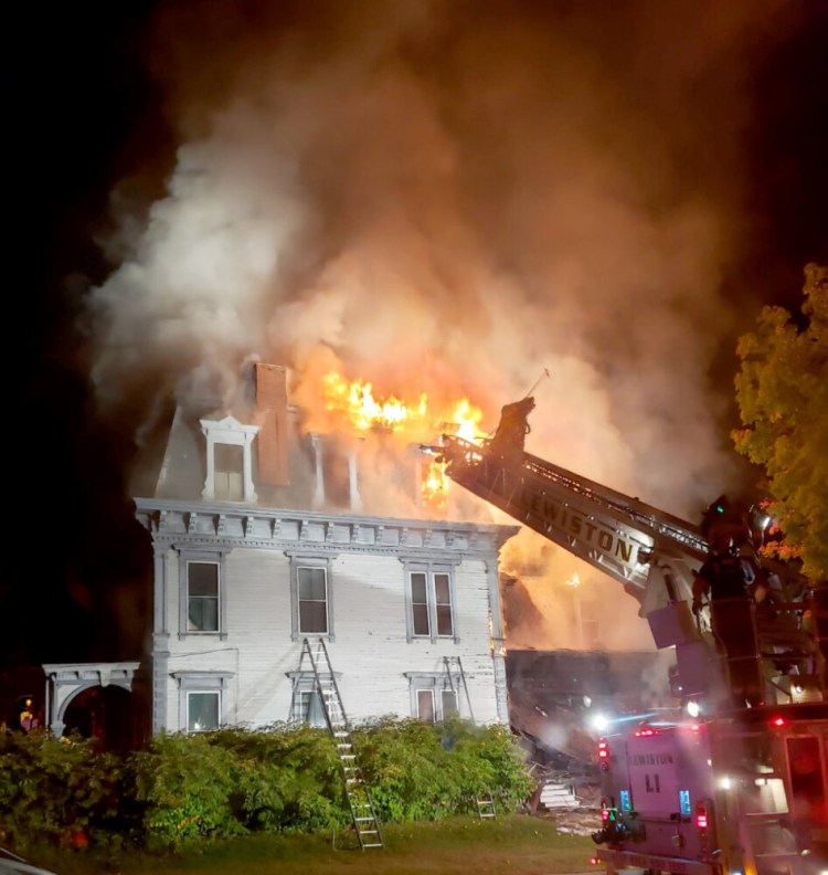 Lewiston Fire Department ladder truck works on one of the sides of a fire at 63 Academy Street in Auburn late Sunday night. (Chasity Latham photo)