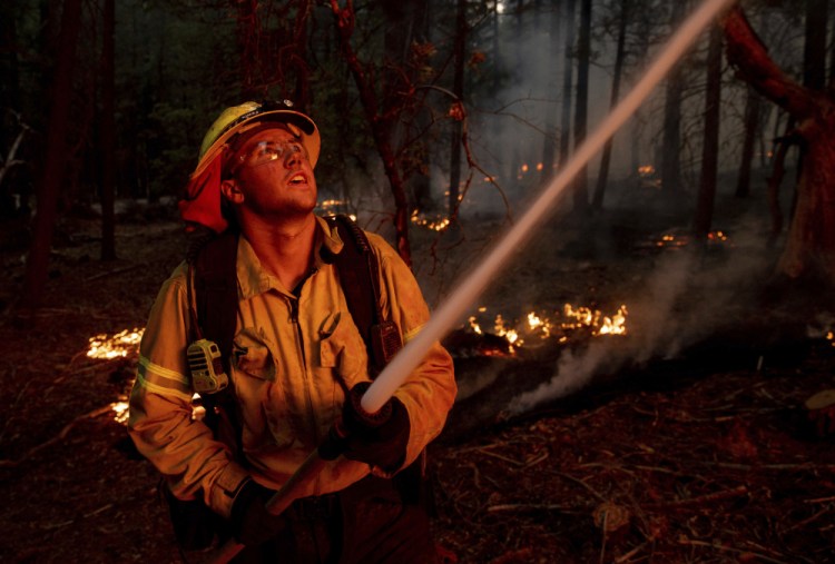 A firefighter hoses down flames from the Dixie Fire in Genesee, Calif., on Saturday.

