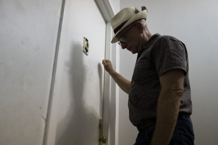 Gary Zaremba knocks on an apartment door as he checks in with tenants to discuss building maintenance at one of his at properties, Thursday, Aug. 12, 2021, in the Queens borough of New York. 
