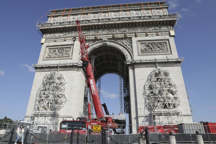 Cranes operate at the Arc de Triomphe in Paris on Tuesday. The "L'Arc de Triomphe, Wrapped" project by late artist Christo and Jeanne-Claude will be on view from, Sept.18 to Oct. 3, 2021. The famed Paris monument will be wrapped in 25,000 square meters of fabric in silvery blue, and with 3,000 meters of red rope. 