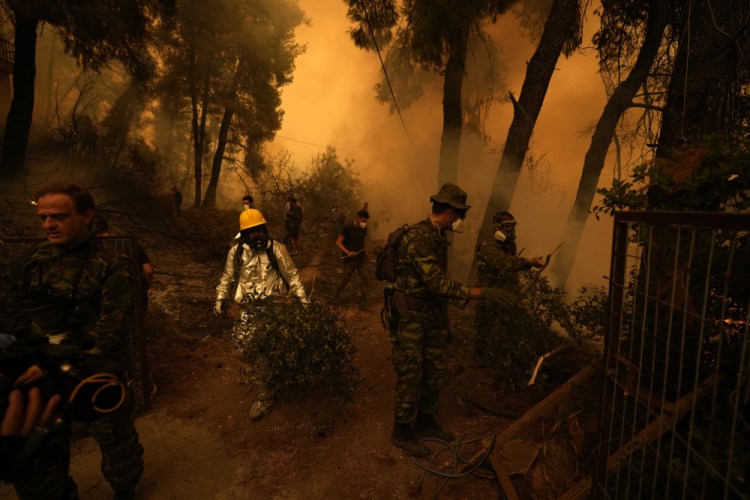 People try to extinguish the flames during a wildfire at Pefki village on Evia island, about 118 miles north of Athens on Sunday. 