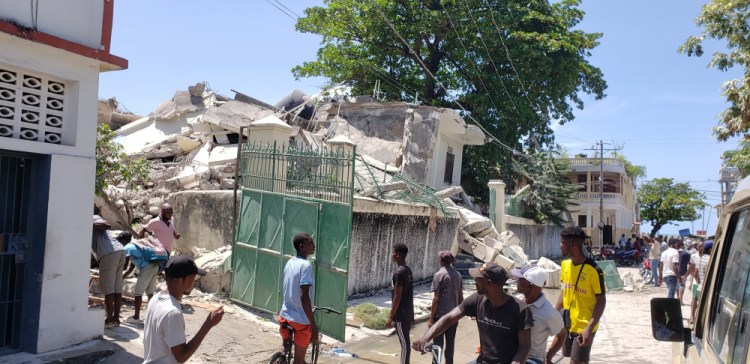 People stand outside the residence of the Catholic bishop after it was damaged by an earthquake Saturday in Les Cayes, Haiti.