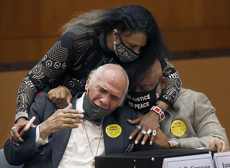 Rose Grayson, niece of Francis DeSales Grayson, top, comforts James Grayson, son of Francis DeSales Grayson, left, and Rudy MCollum, great nephew of Francis DeSales Grayson, one of the Martinsville Seven, after Virginia Gov. Ralph Northam issued posthumous pardons for Grayson and the other six members during a ceremony on Tuesday in Richmond, Va. 