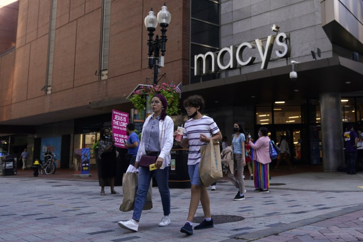 Pedestrians pass the Macy's store in the Downtown Crossing shopping area in Boston on July 14. Americans cut back on their spending last month as a surge in COVID-19 cases kept people away from stores. 