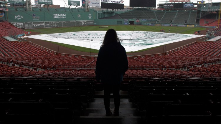 Emma Robertson stares out over Fenway Park in Boston during a rain delay at a recent Red Sox game. Robertson, a Mainer originally from South China, designed the tarp used during rain delays.