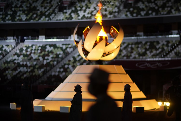 Volunteers stand as International Olympic Committee's President Thomas Bach gives a speech during the closing ceremony Sunday in the Olympic Stadium at the 2020 Summer Olympics in Tokyo, Japan.