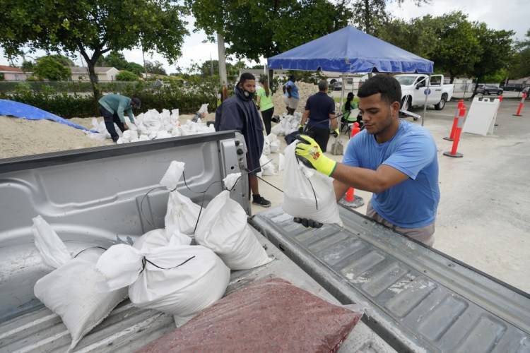 City workers load sandbags at a drive-thru sandbag distribution event for residents ahead of the arrival of rains associated with tropical depression Fred, Friday at Grapeland Park in Miami. 