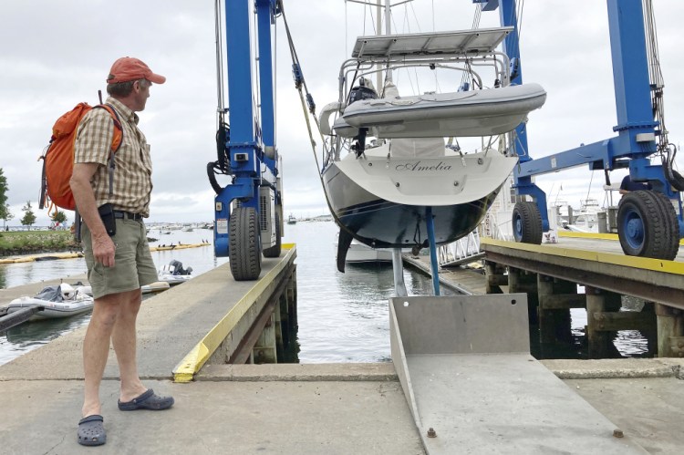 Robin Berthet, of Sheffield, Mass., watches as his sailboat is hauled out of the water onto dry land in advance of an expected storm, on Friday in Plymouth, Mass. 