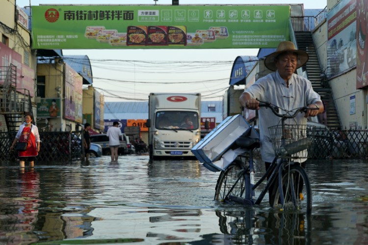 A man carries goods on his bicycle as he walks out of the the Yubei Agricultural and Aquatic Products World in Xinxiang in central China's Henan Province in July. The Intergovernmental Panel on Climate Change report released on Monday, Aug. 9, says warming already is smacking Earth hard and quickly with accelerating sea level rise, shrinking ice and worsening extremes such as heat waves, droughts, floods and storms. 