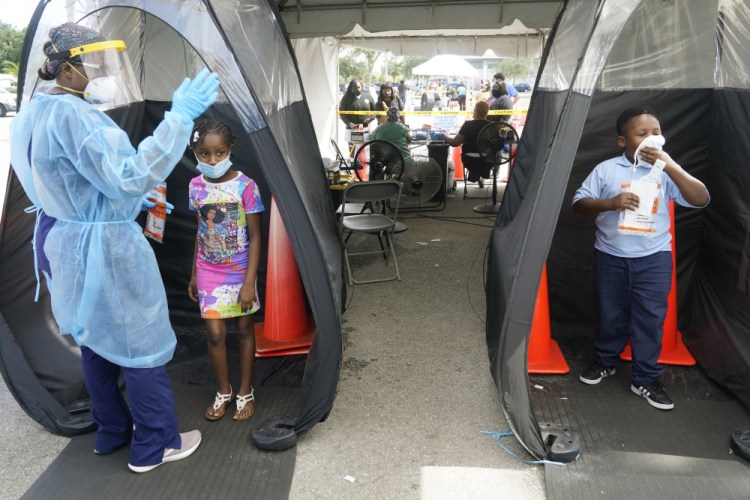 Wenderson Cerisene, 7, right, and his sister Dorah, 9, wait to get tested for COVID-19 on Tuesday in North Miami, Fla. The state has seen a dip in COVID-19 admissions in recent days. 