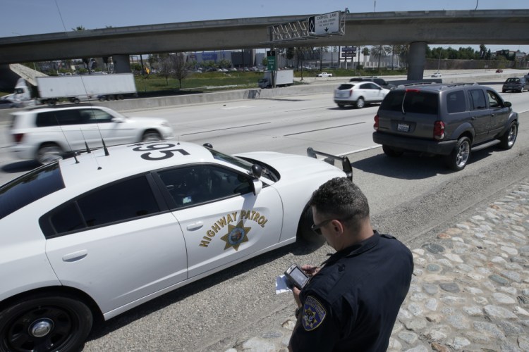 California Highway Patrol officer Troy Christensen runs a driver's license after stopping a motorist along Interstate 5 who was suspected of speeding April 23 in Anaheim, Calif.