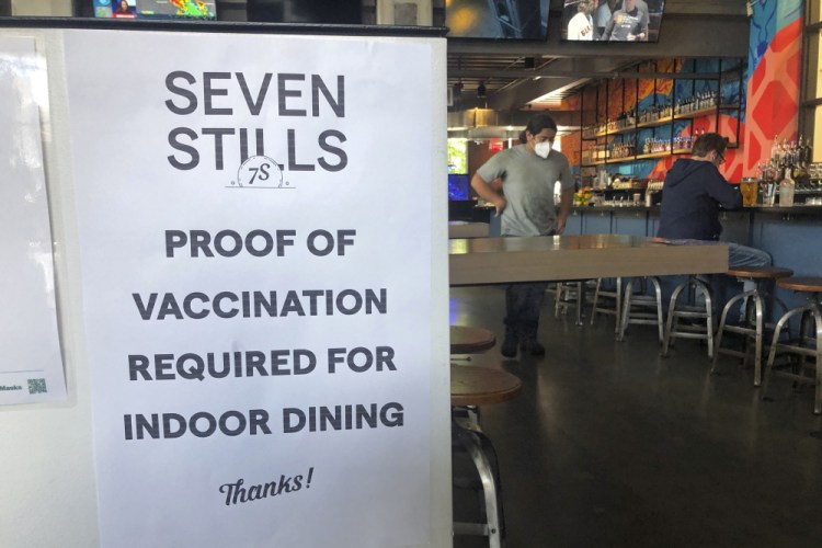 A proof of vaccination sign is posted at a bar in San Francisco on Thursday. Until now, many employers had taken a passive approach to their unvaccinated workers, relying outreach and incentives. But that has been shifting, with vaccine mandates gaining momentum. 