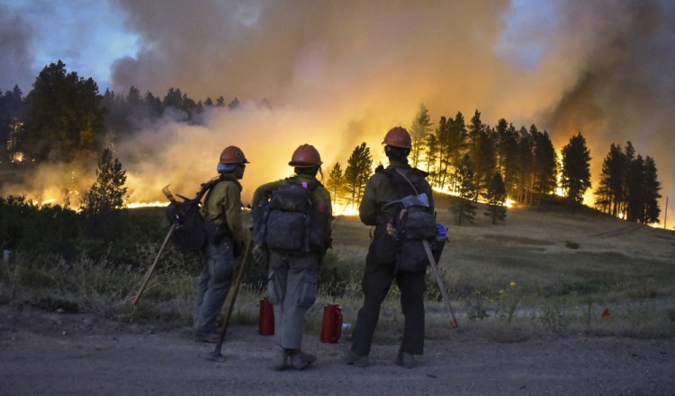 Firefighters watch a hillside burn on the Northern Cheyenne Indian Reservation, Wednesday near Lame Deer, Mont. The Richard Spring fire was threatening hundreds of homes as it burned across the reservation. 


