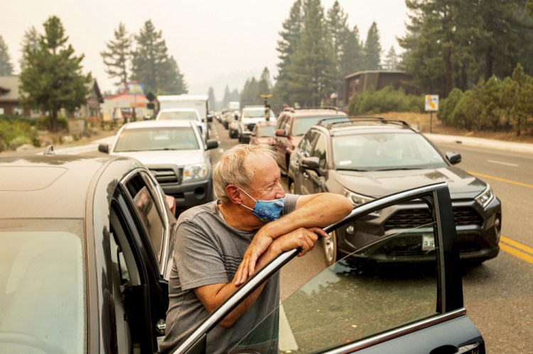 With the Caldor Fire approaching, Jim Mrazek stands outside his vehicle on Highway 50 as evacuee traffic stands still in South Lake Tahoe, Calif., on Monday. Mrazek, who was stopped in that spot for more than an hour, said he was considering taking his boat into the lake instead of trying to drive out. 