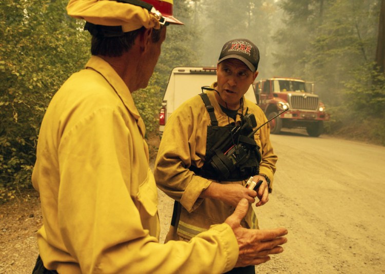 Firefighter Paul Schlange, left, confers while fighting the Caldor Fire  on Hazel Valley Road east of Riverton, Calif., on Thursday.