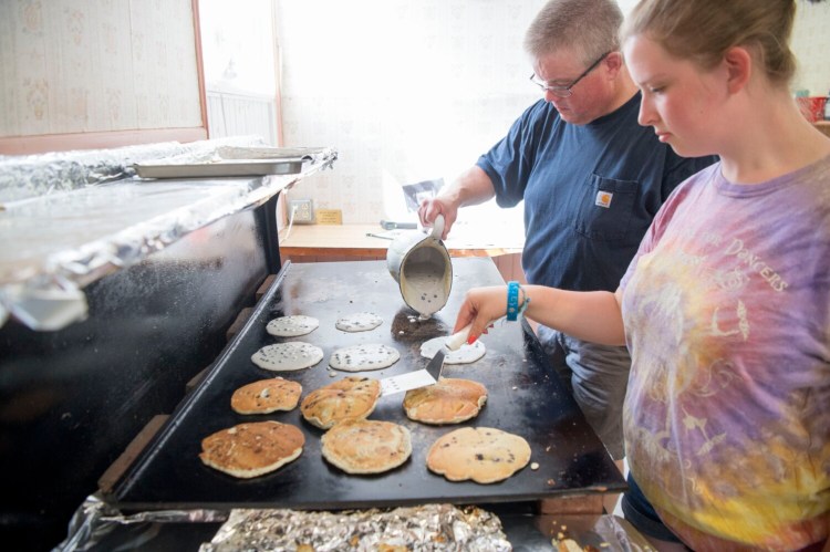 Carl Morrison pours a batch of blueberry pancake mix onto the grill as his daughter Kaitlin flips the flap jacks for the 48th annual blueberry festival at the Winslow Congressional Church on Lithgow Street in Winslow on Aug. 10, 2019. This year's festival is on Saturday. 