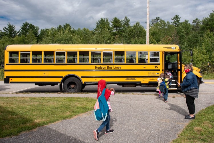 Shawna Haley-Bear, right, helps board the buses on Friday at the McMahon Elementary School in Lewiston. Students are dismissed in groups organized by bus.