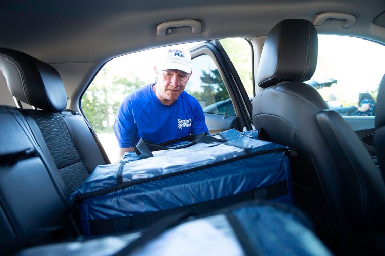 Frank Danforth of Auburn puts meals in the back of his car Tuesday at SeniorsPlus in Lewiston. He volunteers two days a week, making 30 deliveries each Tuesday with the Meals on Wheels program and fewer on Thursdays.