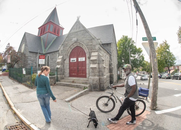 Jeanette Cunningham walks with her friend Lee Heath on Wednesday along the sidewalk in front of the Trinity Jubilee Church in Lewiston. Plans are in the works to turn Trinity Church into a community center, expanding Trinity Jubilee in the basement and adding new elements upstairs.