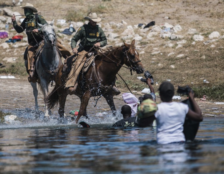 U.S. Customs and Border Protection mounted officers attempt to contain migrants as they cross the Rio Grande from Ciudad Acuña, Mexico, into Del Rio, Texas, Sunday, Sept. 19. 