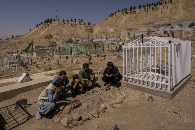 The Ahmadi family prays last week next to graves of family members killed by a U.S. drone strike, in Kabul, Afghanistan.   Sorry is not enough for the Afghan survivors of an errant U.S. drone strike that killed 10 members of their family, including seven children. (AP Photo/Bernat Armangue, File)