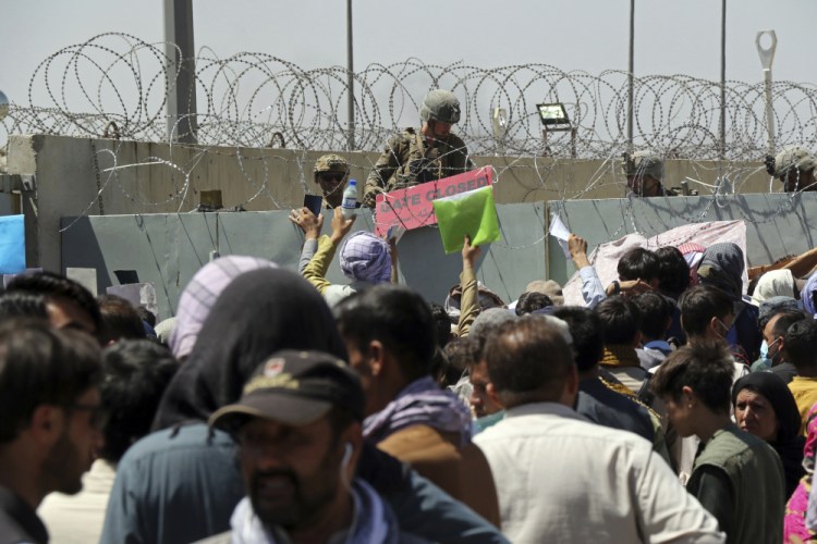 A U.S. soldier holds a sign indicating a gate is closed as hundreds of people gather near an evacuation control checkpoint on the perimeter of the Hamid Karzai International Airport on Aug. 26 in Kabul, Afghanistan. 