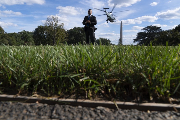 A Secret Service agent stands guard as Marine One with President Biden abroad lifts off from the South Lawn of the White House in Washington on Monday. 