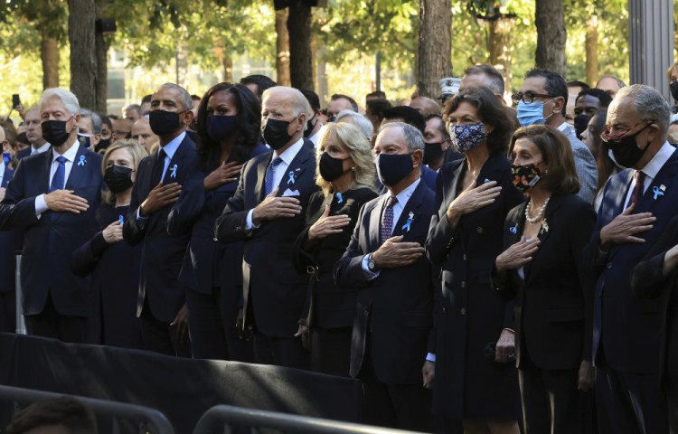 From left, former President Bill Clinton, former First Lady Hillary Clinton, former President Barack Obama, Michelle Obama, President Biden, first lady Jill Biden, former New York City Mayor Michael Bloomberg, Bloomberg's partner Diana Taylor, Speaker of the House Nancy Pelosi, D-Calif., and Senate Majority Leader Charles Schumer, D-N.Y., stand for the national anthem during the annual 9/11 Commemoration Ceremony at the National 9/11 Memorial and Museum on Saturday in New York.