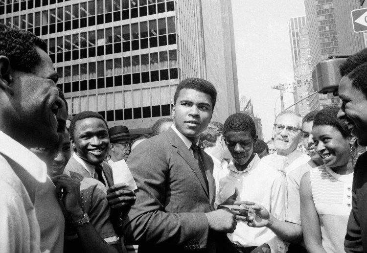 Muhammad Ali, former world heavyweight boxing champion, is surrounded by autograph seekers at 51st Street and Sixth Avenue in Manhattan borough of New York, Aug. 23, 1968. He was en route to a television studio when pedestrians mobbed him. The former champ says he may fight Joe Frazier on an Indian reservation, which he claims would not place such a bout under government control. (AP Photo/Anthony Camerano)