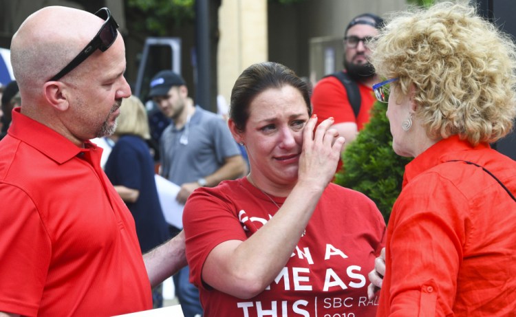 Jules Woodson, center, of Colorado Springs, Colo., is comforted by her boyfriend Ben Smith, left, and Christa Brown while demonstrating outside the Southern Baptist Convention's annual meeting in Birmingham, Ala. on June 11, 2019. First-time attendee Woodson spoke through tears as she described being abused sexually by a Southern Baptist minister. 