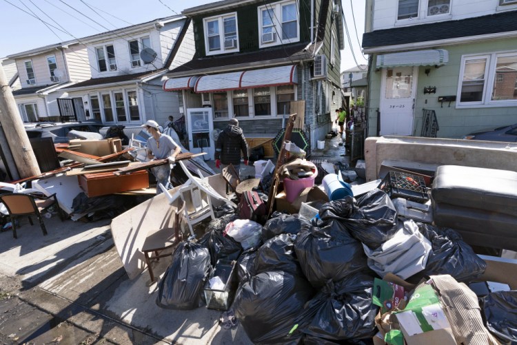 People clear debris and damaged belongings from their homes in the Queens borough of New York on Sept. 3.  