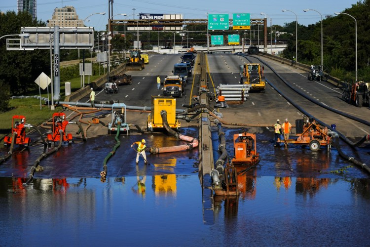 Workers pump water from a flooded section of Interstate 676 in Philadelphia on Friday in the aftermath of downpours and high winds from the remnants of Hurricane Ida that hit the area.