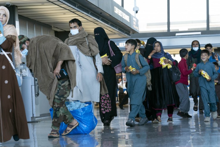 People evacuated from Kabul, Afghanistan, walk through the terminal before boarding a bus after they arrived at Washington Dulles International Airport, in Chantilly, Va., on Thursday, Sept. 2. 
