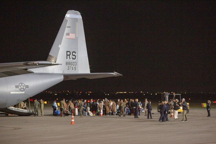 Families evacuated from Kabul, Afghanistan, walk past a U.S Air Force plane that they arrived on at Kosovo's capital Pristina International Airport on Aug. 29. 