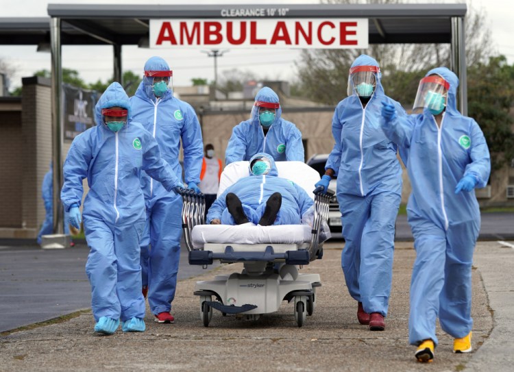 A patient is taken on a stretcher into the United Memorial Medical Center  after going through testing for COVID-19 in Houston in March 2020, as the coronavirus pandemic began tightening its grip on the U.S. People were lined up in their cars in a line that stretched over two miles to be tested in the drive-thru testing for coronavirus. 