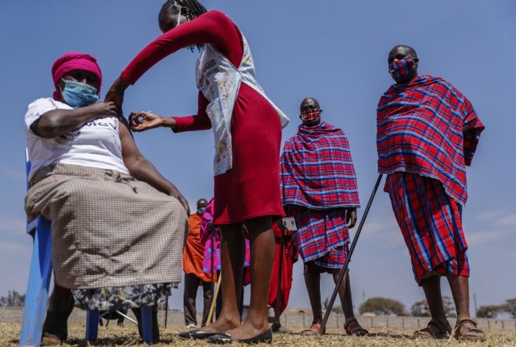 Maasai men queuing to receive the AstraZeneca coronavirus vaccine look over as a woman receives a jab Saturday at a clinic in Kimana, southern Kenya.