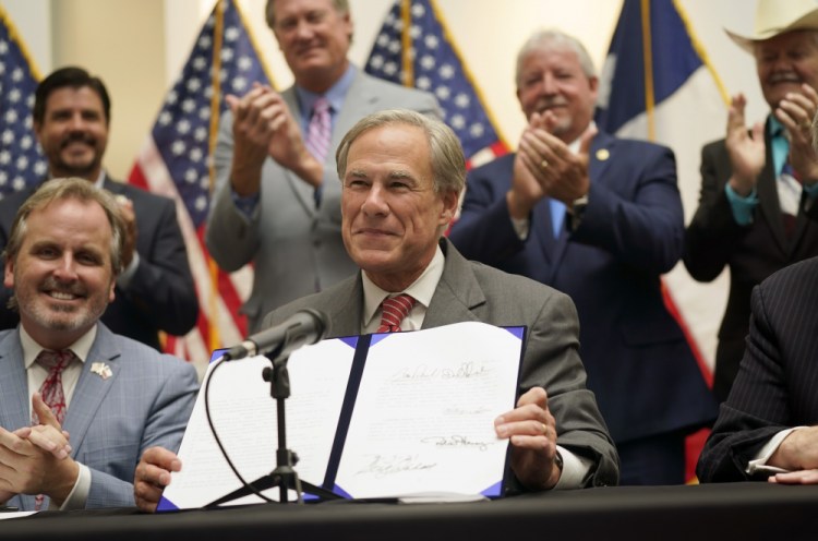 Texas Gov Greg Abbott shows off Senate Bill 1 after he signed it into law in Tyler, Texas, Tuesday, Sept. 7, 2021. The sweeping bill signed Tuesday by the two-term Republican governor further tightens Texas’ strict voting laws. 