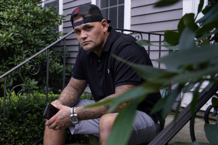 Mike Gilpatrick, who as a teenager was incarcerated at the Youth Development Center, poses on the front steps of his home, Wednesday, Sept. 8, 2021, in Nashua, N.H. 