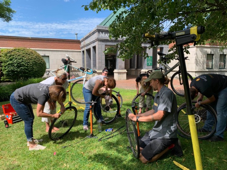 Shannon Bell of the Bicycle Coalition of Maine, center foreground, leads one of the organization's "Fix-A-Bike" workshops in 2019 outside of Martin's Point Health Care in Portland. The pictured workshop was prior to the COVID-19 pandemic.