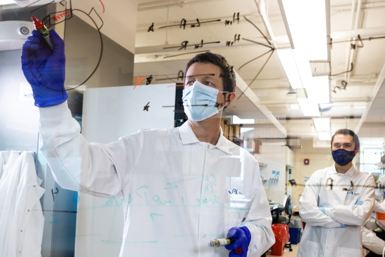 Ryan Tewhey is shown working in his research lab at The Jackson Laboratory in Bar Harbor in September. Tewhey and his team, including research associate Daniel Berenzy, right, have been conducting genomic sequencing of positive COVID-19 tests in Maine to look for variants, such as delta.
