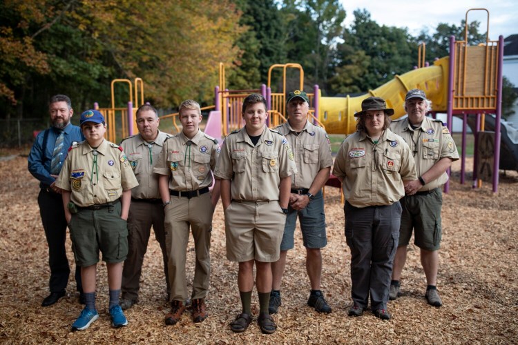 BUXTON, ME - SEPTEMBER 30: From left, Chad Poitras, Mathieu Poitras, 12, Danny Rose, Sawyer Rose, 13, Luke Plummer, 16, Garrett Plumner, Nicholas Hobson, 16, and Eric Hobson pose for a portrait in front of the the Eliza Libby School playground on Thursday, September 30, 2021. The school closed about a decade ago the playground was completely overgrown. Plummer, a junior at Bonny Eagle, took on overseeing the playground’s restoration - his community project to become an Eagle Scout and he did the work alongside members from his Boy Scout Troop 349 and many of their family members. (Staff photo by Brianna Soukup/Staff Photographer)