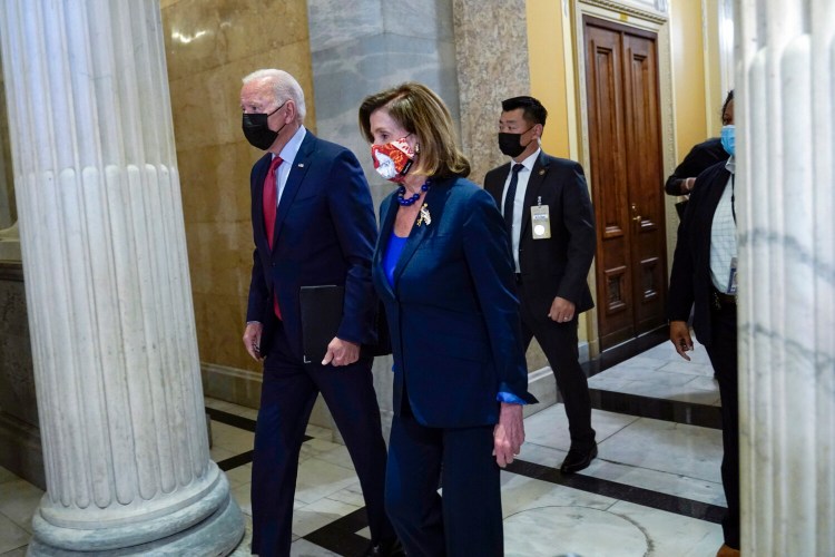President Biden walks with House Speaker Nancy Pelosi on Capitol Hill on Friday for a meeting with the House Democratic caucus to try to resolve an impasse to getting the president's agenda through Congress. 