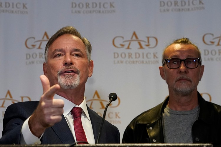 Attorney Gary Dordick, left, makes a gun pointing gesture, alongside his client Serge Svetnoy, chief of lighting on the "Rust" film set, after announcing a lawsuit against Alec Baldwin and others, Wednesday, Nov. 10, 2021, in Beverly Hills, Calif. Svetnoy filed the lawsuit over Baldwin's fatal shooting of cinematographer Halyna Hutchins on the New Mexico set of the Western, alleging negligence that caused him "severe emotional distress" that will haunt him forever. (AP Photo/Damian Dovarganes)