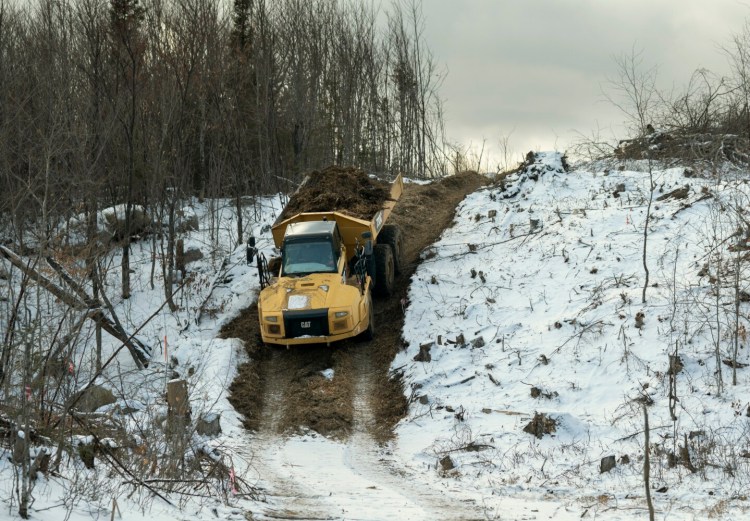 Carrying a load of wood debris, a driver navigates a dump truck down a steep hill along the NECEC corridor in Johnson Mountain Township on Nov. 30. 