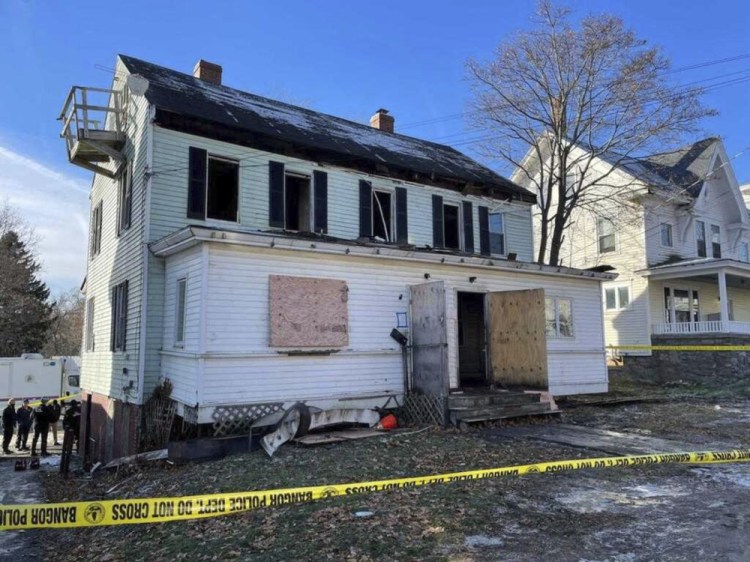 Officials work at the scene of a house fire in Bangor on Sunday. Three people died and two others were injured, according to fire officials.