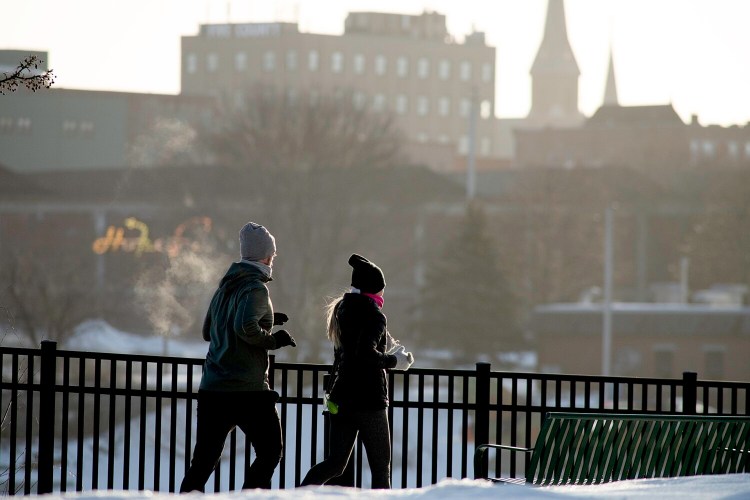 Two runners exercise one morning in January 2022 on the Lewiston-Auburn Riverwalk in Auburn. The path, which connects the two cities, follows the Androscoggin River.